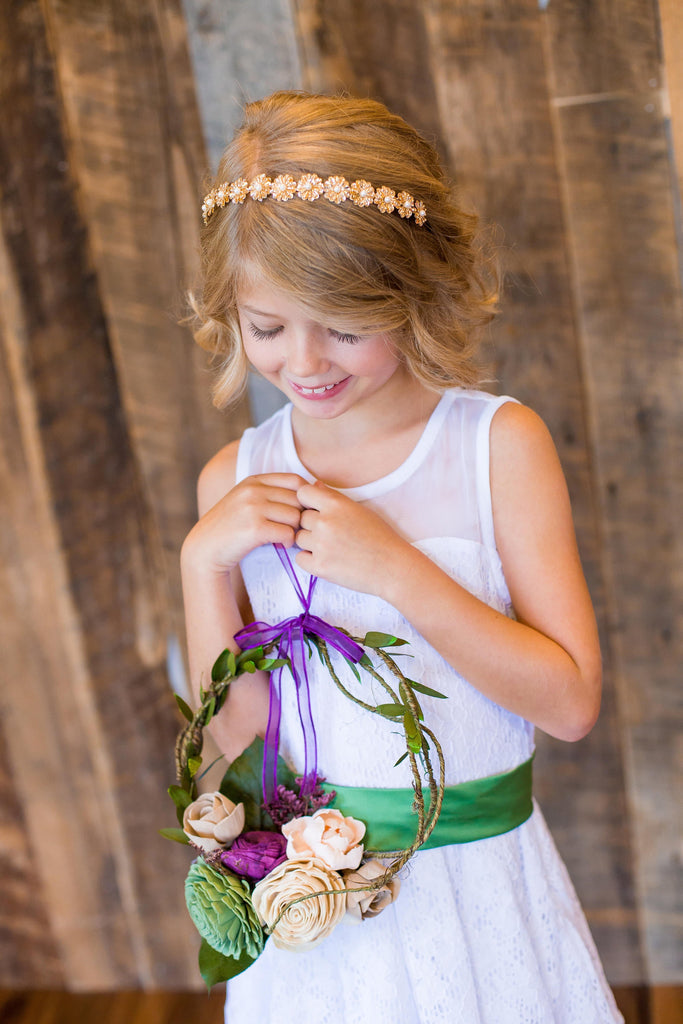 flower girl carrying wreath made of sola wood flowers being held by flower girl for wedding