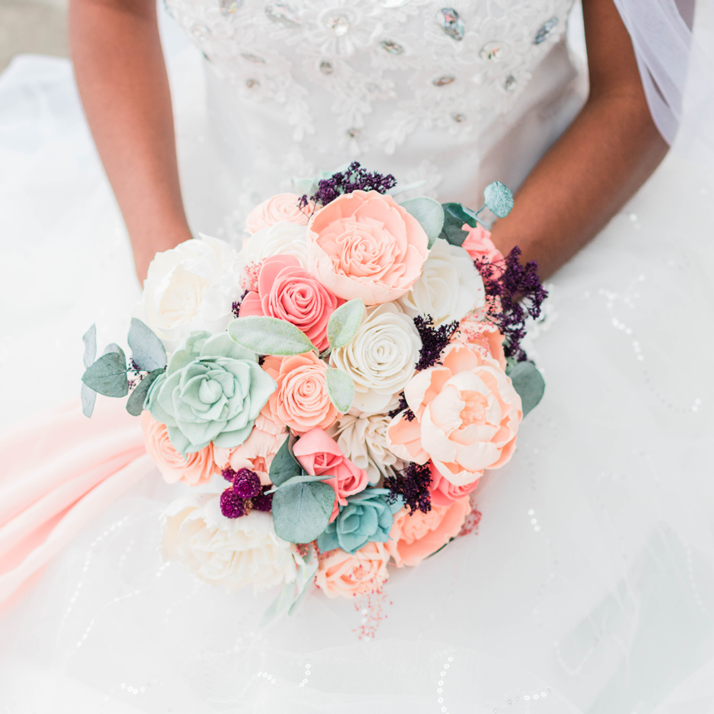 coral and peach wedding bouquet made from sola wood flowers being held by a bride