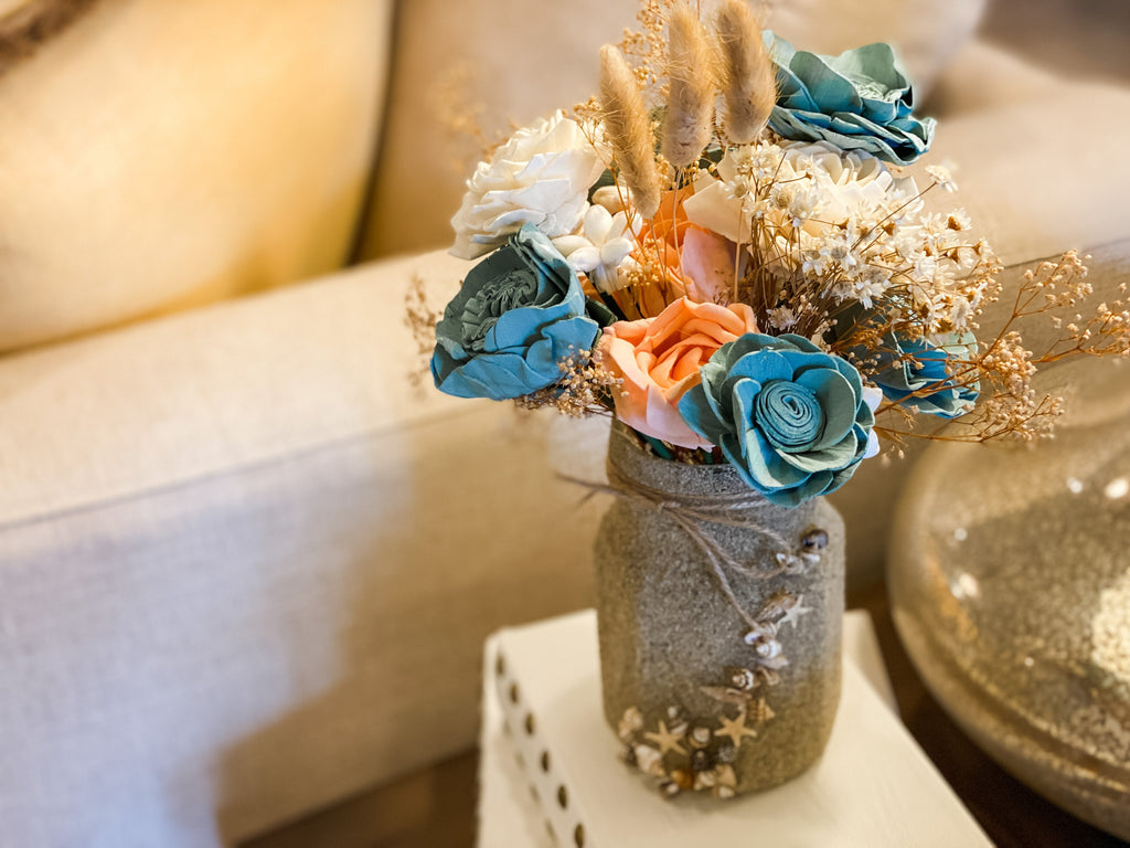 faux flower arrangement for beach house in coral, and teal in mason jar with sand