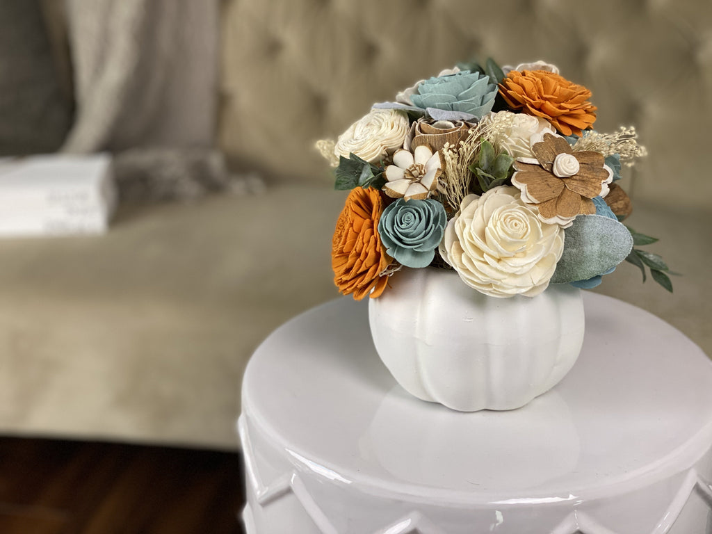 fall flower thanksgiving table centerpiece ideas with sola wood flowers arranged in a white pumpkin